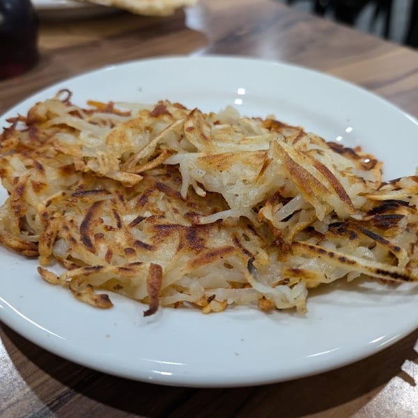 Golden brown, crispy hash browns on a white plate, ready to be enjoyed for breakfast.